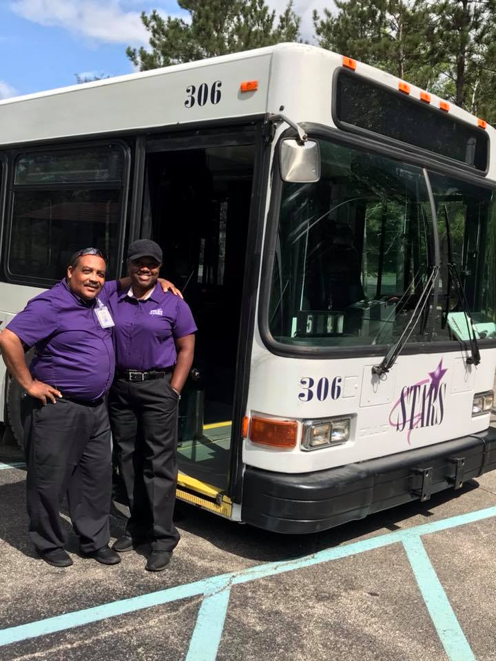 two men standing next to a bus